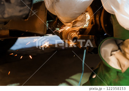 Close-up of a Mechanic Performing Precision Metal Work Under a Vehicle 122358153