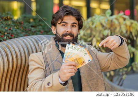 Successful rich happy young Indian man holding euro bill money cash fan on downtown city street Successful rich happy young Indian man holding euro bill money cash fan on downtown city street 122358186