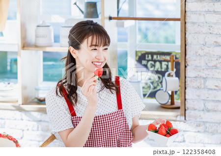 キッチンでイチゴをつまみ食いする女性 122358408