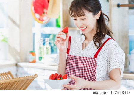 キッチンでイチゴをつまみ食いする女性 122358418