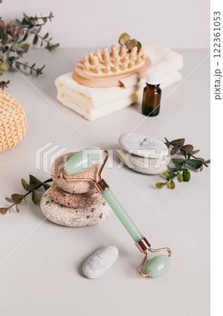 Jade roller for massage, pebbles and spa items on table vertical view Jade roller for massage, pebbles and spa items on table vertical view 122361053
