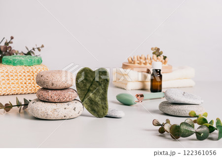 Jade gua sha massager, pebbles and spa items on table Jade gua sha massager, pebbles and spa items on table 122361056