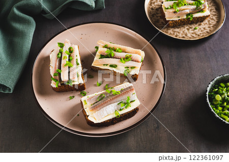 Norwegian smorrebrod made from rye bread, butter and salted herring on a plate on a table Norwegian smorrebrod made from rye bread, butter and salted herring on a plate on a table 122361097