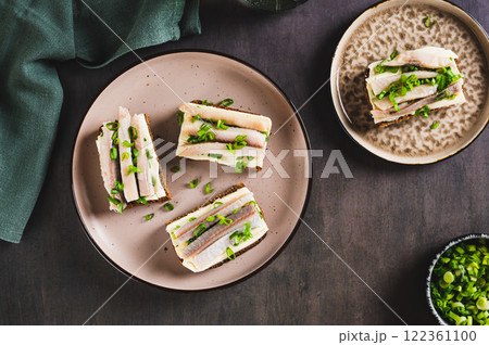 Scandinavian open sandwiches on rye bread with butter and salted herring on a plate top view 122361100