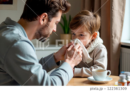 Father wiping his nose with handkerchief on his cold-stricken son. Parental care and treatment during cold season Father wiping his nose with handkerchief on his cold-stricken son. Parental care and treatment during cold season 122361309