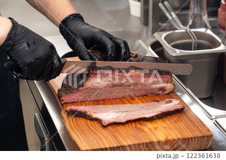 Cutting smoked brisket into slices in the kitchen 122361638