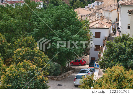 Charming Mediterranean village view with trees, houses, and parked vehicles 122361762