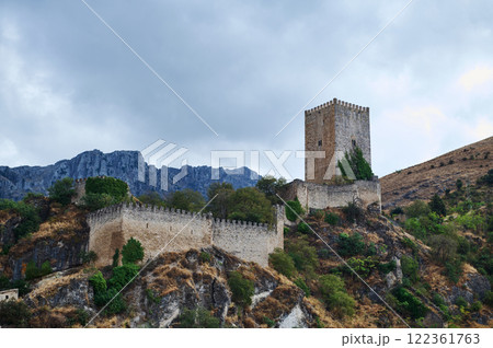 Historic stone castle surrounded by nature on a hill under cloudy skies Historic stone castle surrounded by nature on a hill under cloudy skies 122361763