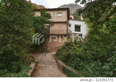 Rustic stone house surrounded by lush greenery and natural landscape Rustic stone house surrounded by lush greenery and natural landscape 122361773