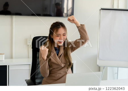 Businesswoman sitting at desk on couch in workplace or at home working on laptop and analyzing data on charts and graphs and writing on papers to make business plan and strategies for company. Businesswoman sitting at desk on couch in workplace or at home working on laptop and analyzing data on charts and graphs and writing on papers to make business plan and strategies for company. 122362043