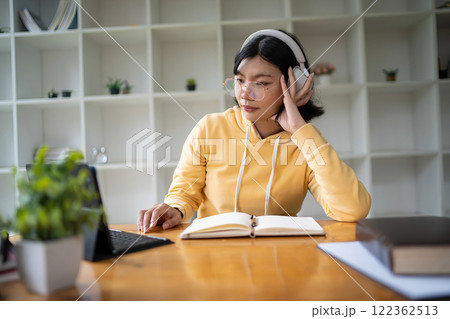 Intelligent young woman having online lessons on laptop, drinking coffee and taking notes, Intelligent young woman having online lessons on laptop, drinking coffee and taking notes, 122362513