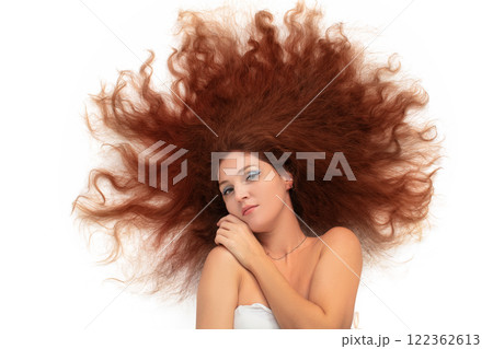 A young beautiful woman with scattered curly long luxurious hair on a white background. A young beautiful woman with scattered curly long luxurious hair on a white background. 122362613