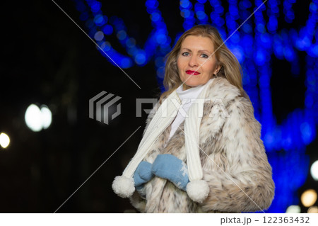 Portrait of a beautiful middle-aged woman in a fur coat in the lights of the evening city. 122363432