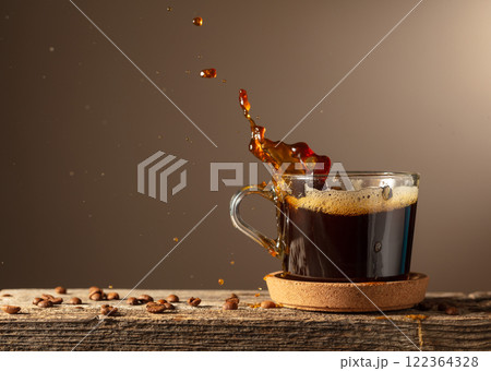 Black coffee in glass cup on a brown background. Black coffee in glass cup on a brown background. 122364328