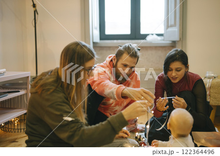 A beautiful candid family moment featuring a baby, friends, and joyous interactions all around 122364496