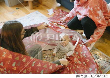 Experience the joyful moments of unwrapping colorful holiday gifts together with your baby 122364512