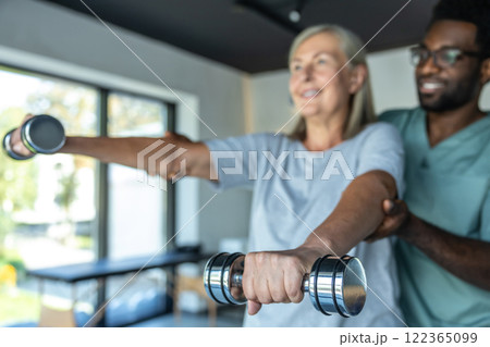 Man chiropractor in hospital assisting mature woman with pain relief exercises for physical recovery Man chiropractor in hospital assisting mature woman with pain relief exercises for physical recovery 122365099