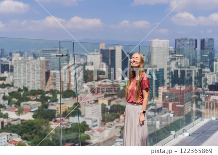 Female tourist or businesswoman standing on a skyscraper rooftop with a panoramic view of Mexico City. Travel or international business in Mexico concept Female tourist or businesswoman standing on a skyscraper rooftop with a panoramic view of Mexico City. Travel or international business in Mexico concept 122365869