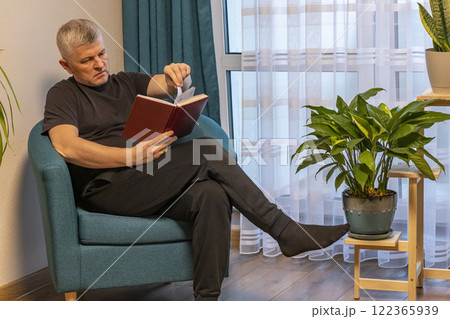 Man sitting in the cozy corner in the apartment on comfortable arm chair. Man sitting in the cozy corner in the apartment on comfortable arm chair. 122365939
