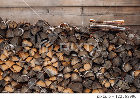 Weathered firewood neatly stacking against wooden wall, capturing rural russian landscape with rustic textural charm Weathered firewood neatly stacking against wooden wall, capturing rural russian landscape with rustic textural charm 122365996