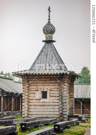 Weathered wooden chapel standing tall with cross adorned roof, symbolizing spiritual legacy within rustic russian village landscape 122366021