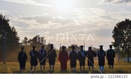 Students in graduation gowns celebrating by tossing their hats in the air Students in graduation gowns celebrating by tossing their hats in the air 122366125
