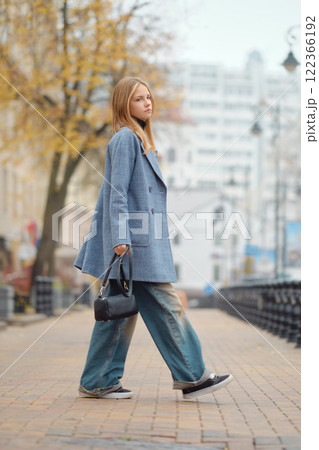 A fashionable young woman strolls a city street on a cloudy day in her trendy outfit A fashionable young woman strolls a city street on a cloudy day in her trendy outfit 122366192
