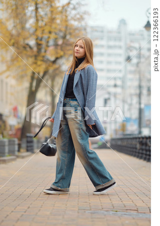Stylish young woman walking on a brick path in an urban area during autumn 122366193