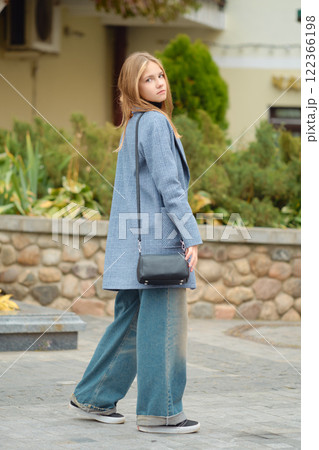 Stylish woman in casual outfit poses confidently in urban garden setting Stylish woman in casual outfit poses confidently in urban garden setting 122366198
