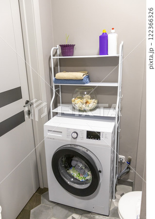 Shelf above the washing machine with household items 122366326