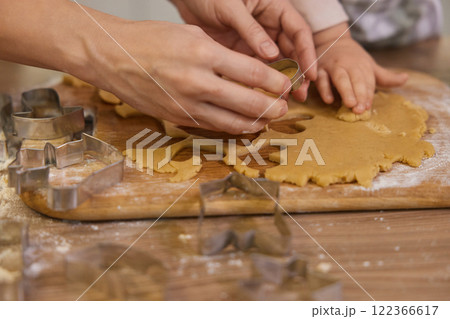 close-up, hands of mother and little child cutting cookies of raw gingerbread dough in kitchen, Christmas traditions close-up, hands of mother and little child cutting cookies of raw gingerbread dough in kitchen, Christmas traditions 122366617