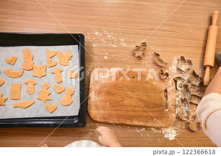 raw gingerbread dough for cookies on baking tray and cookie cutters on table, top view 122366618