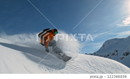 Snowboard rider riding down fresh powder during sunny day , Alpine scenery Snowboard rider riding down fresh powder during sunny day , Alpine scenery 122366836