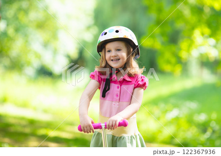 Little girl riding a colorful scooter Little girl riding a colorful scooter 122367936
