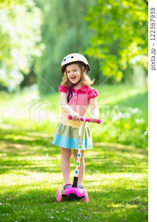 Little girl riding a colorful scooter Little girl riding a colorful scooter 122367939