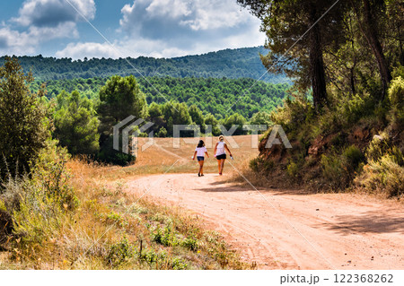 Mother with her daughter walking through nature along a forest path in Anoia, Barcelona	 122368262
