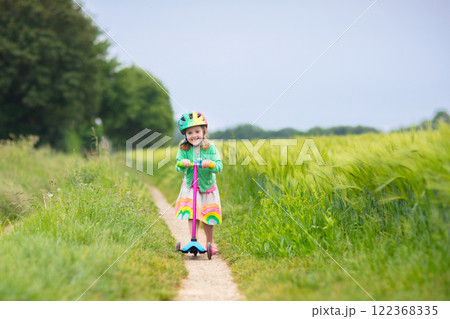 Litte girl riding scooter. Child playing outdoor. Litte girl riding scooter. Child playing outdoor. 122368335