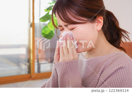 辛そうに鼻水をかむ若いアジア人女性 122369114