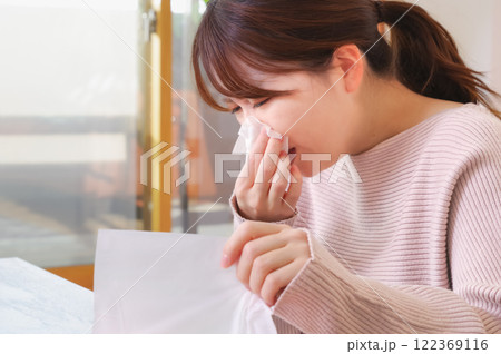 辛そうに鼻水をかむ若いアジア人女性 122369116