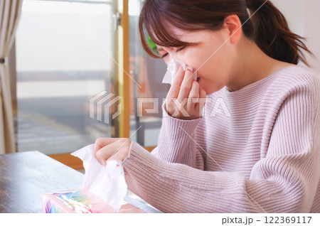 辛そうに鼻水をかむ若いアジア人女性 122369117