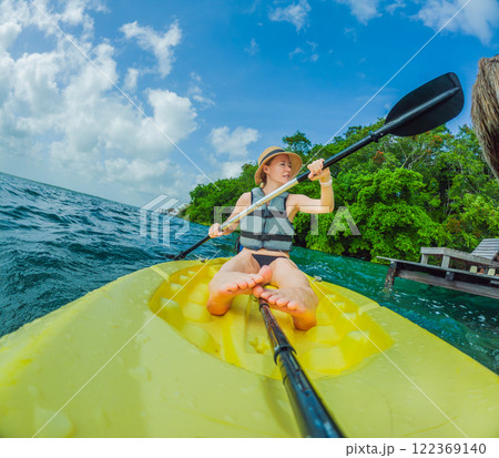 Unaltered woman tourist kayaking on the serene turquoise waters of Lake Bacalar, Mexico, surrounded by natural beauty. Adventure, relaxation, and outdoor travel concept in a peaceful tropical Unaltered woman tourist kayaking on the serene turquoise waters of Lake Bacalar, Mexico, surrounded by natural beauty. Adventure, relaxation, and outdoor travel concept in a peaceful tropical 122369140