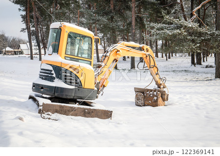 Abandoned excavator in the snow on a winter day due to unsuitable season for construction works Abandoned excavator in the snow on a winter day due to unsuitable season for construction works 122369141