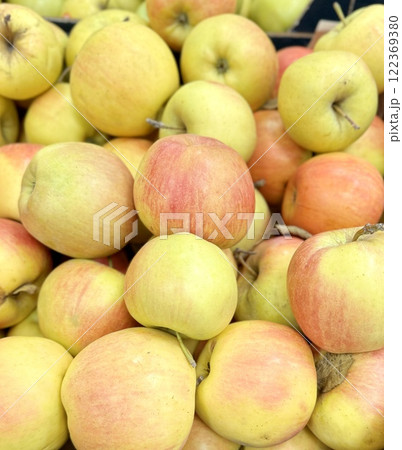 Box filled with fresh natural bio organic red yellow green apples placed on counter in local food market. Close-up Box filled with fresh natural bio organic red yellow green apples placed on counter in local food market. Close-up 122369380