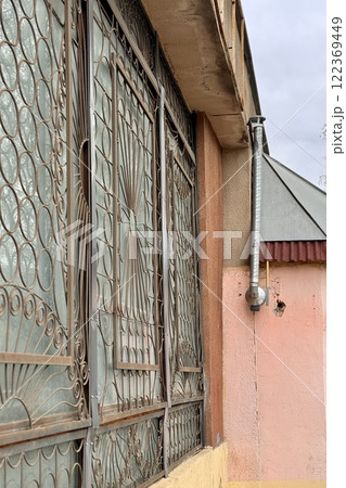 A metal pipe is attached to the wall of a brick building, which removes smoke from the room. This is a device for air circulation 122369449