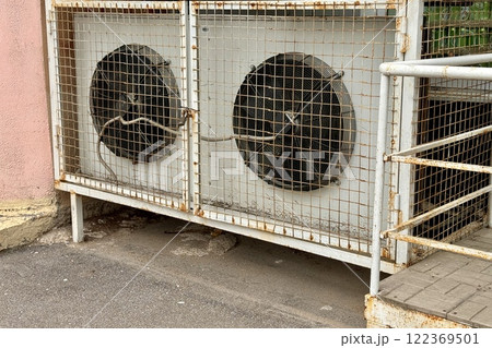 Two refrigeration fans for industrial cold rooms of supermarket. Air coolers refrigeration evaporators installed on ground have metal wire crate, closed doors with hinged metal lock for maintenance 122369501