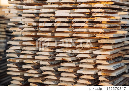 Wooden planks neatly stacking, creating textured surface, representing lumber industry's raw material preparation and natural wood characteristics Wooden planks neatly stacking, creating textured surface, representing lumber industry's raw material preparation and natural wood characteristics 122370847