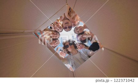 Happy high school students enjoying their summer vacation together, looking inside a large cardboard box 122371042