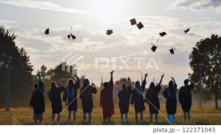 Graduates tossing their mortarboards into the air at sunset, commemorating their academic success 122371043