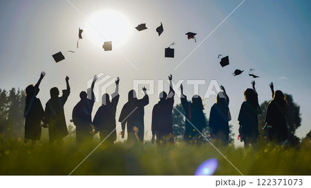 Graduates happily tossing their caps into the air at sunset, commemorating their accomplishments and fresh starts 122371073