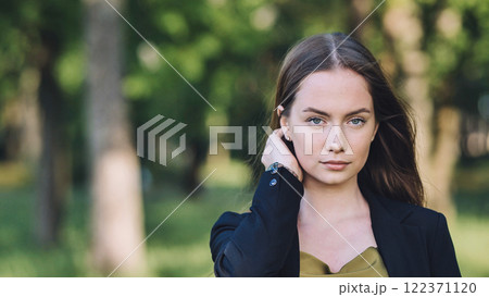 Portrait of a confident young businesswoman adjusting her hair while standing in a serene green park Portrait of a confident young businesswoman adjusting her hair while standing in a serene green park 122371120